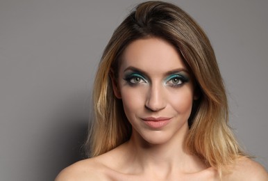 Photo of Young woman with evening makeup on grey background. Eye shadow product
