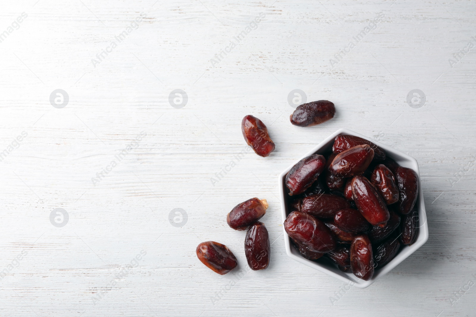 Photo of Bowl of sweet dates on wooden background, top view with space for text. Dried fruit as healthy snack