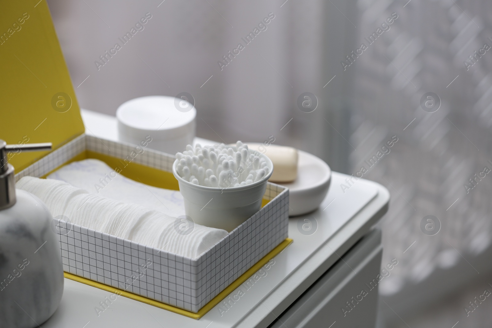 Photo of Cotton buds and pads in box on white table indoors