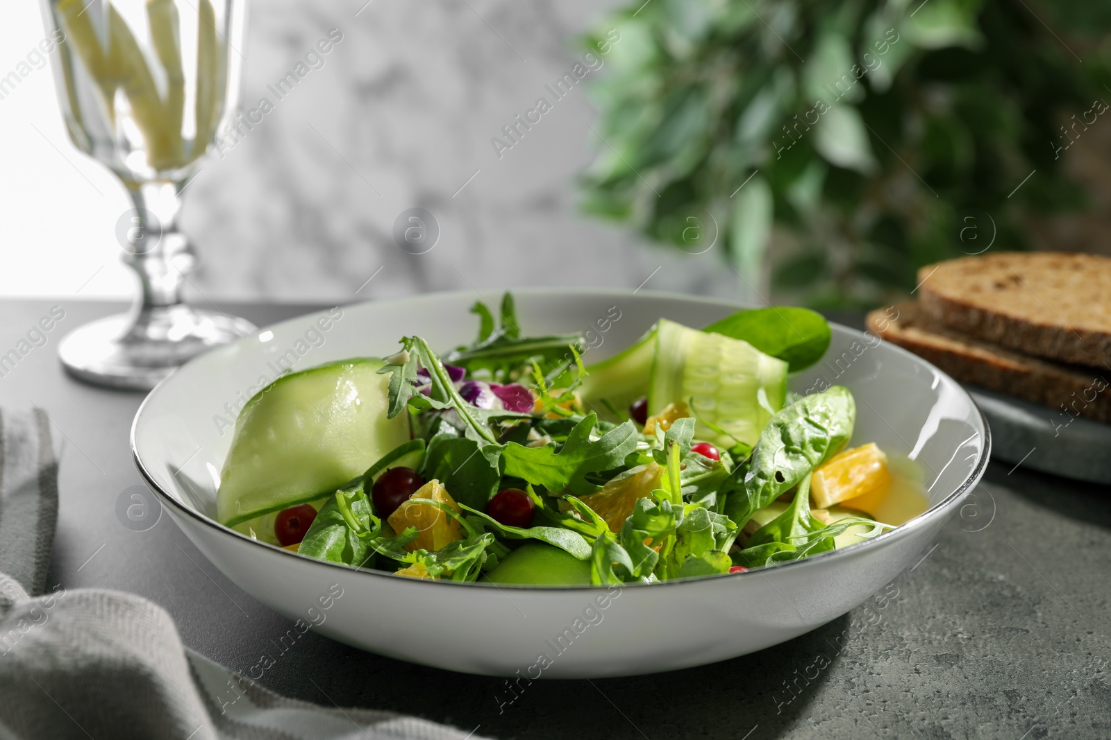 Photo of Delicious salad with cucumber and orange slices on gray table