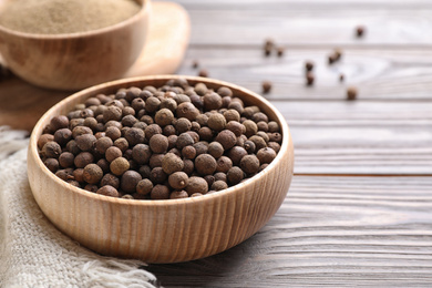 Photo of Peppercorns on light grey wooden table, closeup