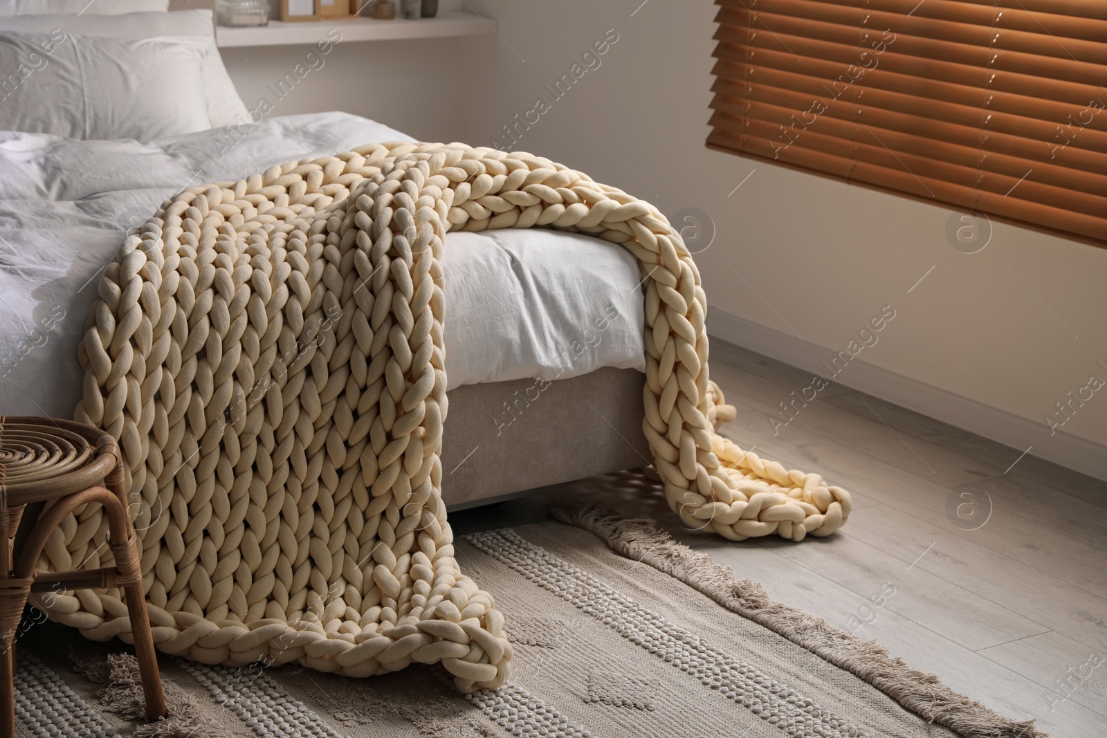 Photo of Soft chunky knit blanket on bed in stylish room interior