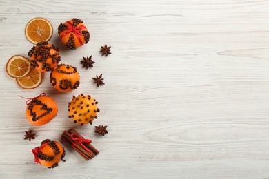 Photo of Flat lay composition with pomander balls made of fresh tangerines and cloves on white wooden table, space for text