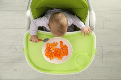 Photo of Cute little baby eating carrot, top view