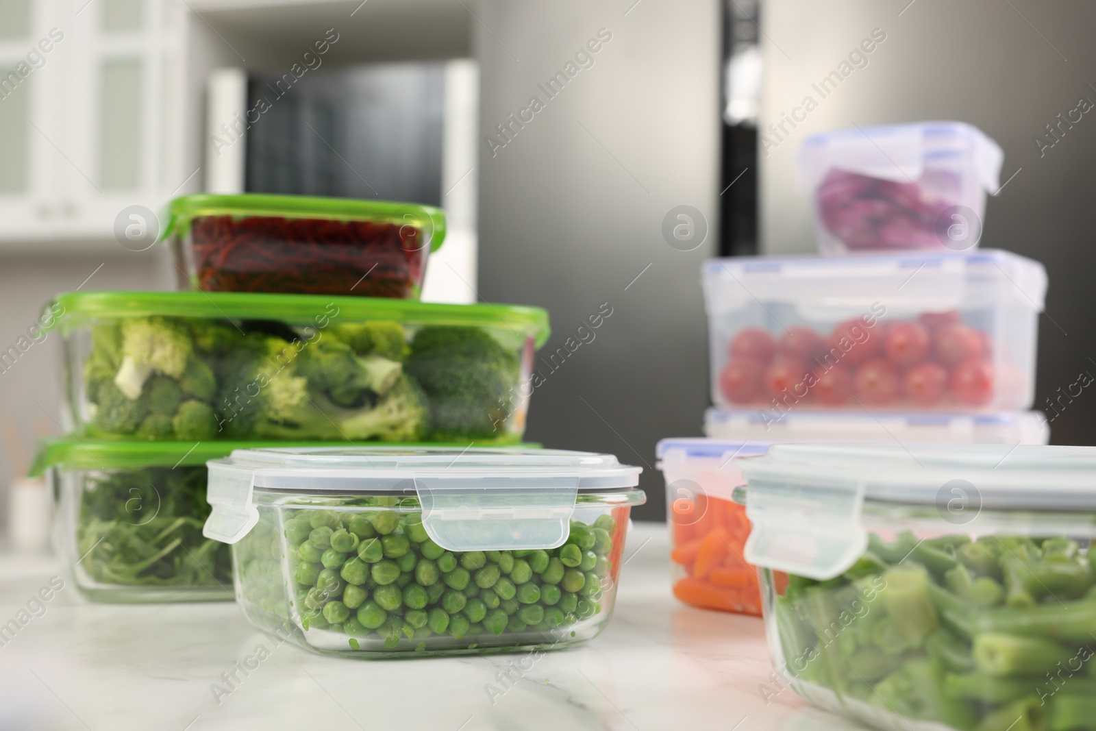 Photo of Containers with different fresh products on white marble table in kitchen, closeup. Food storage