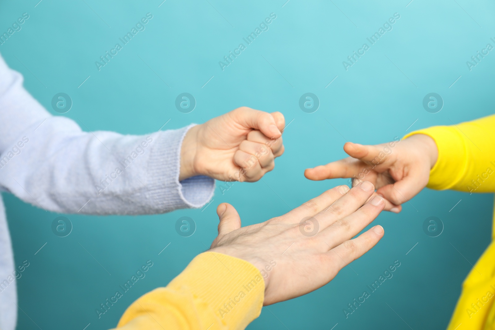 Photo of People playing rock, paper and scissors on light blue background, closeup