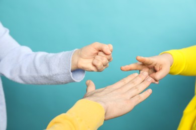 People playing rock, paper and scissors on light blue background, closeup