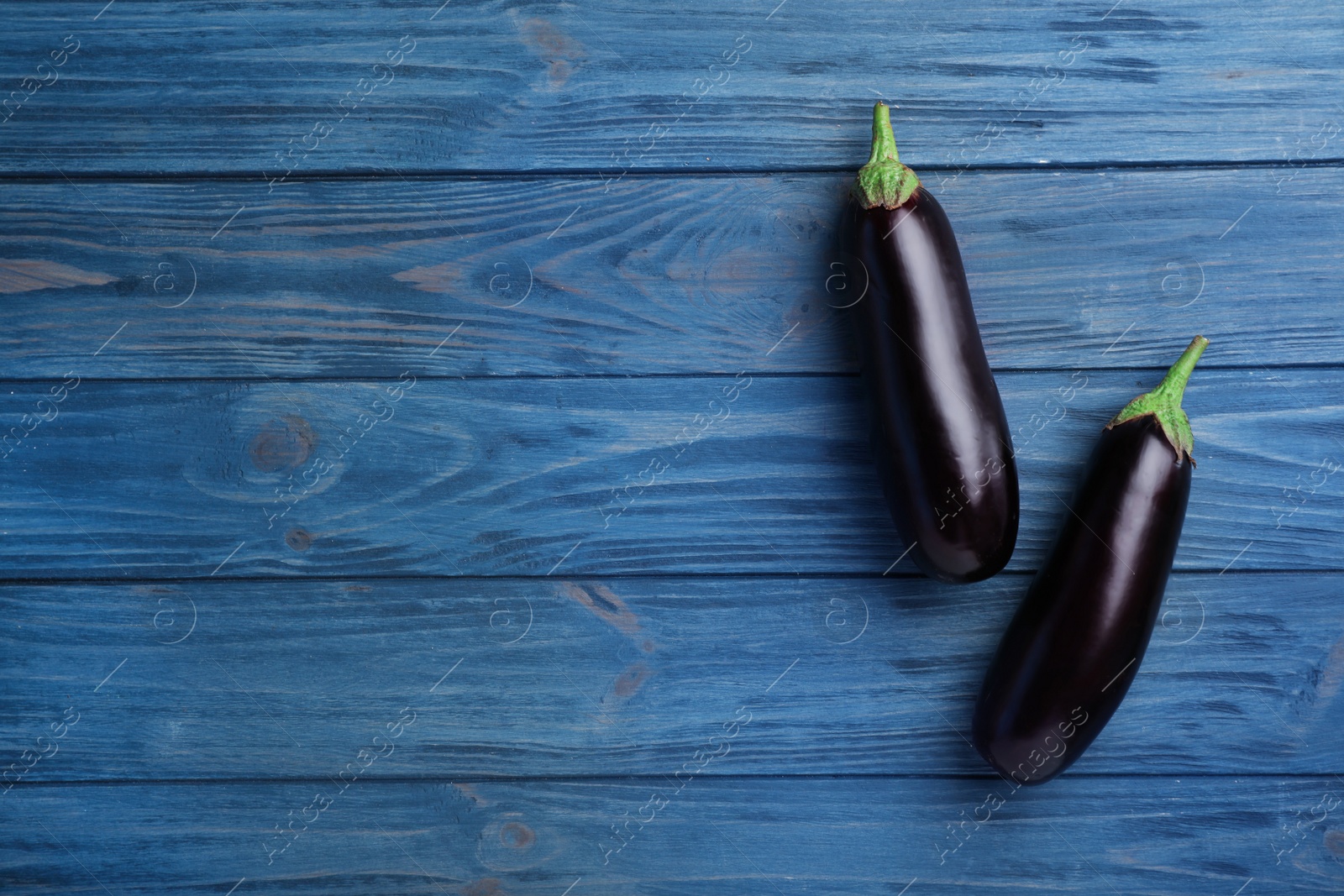 Photo of Raw ripe eggplants on wooden background, top view