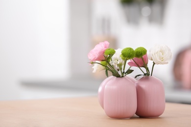 Photo of Vases with beautiful flowers on table in kitchen interior. Space for text