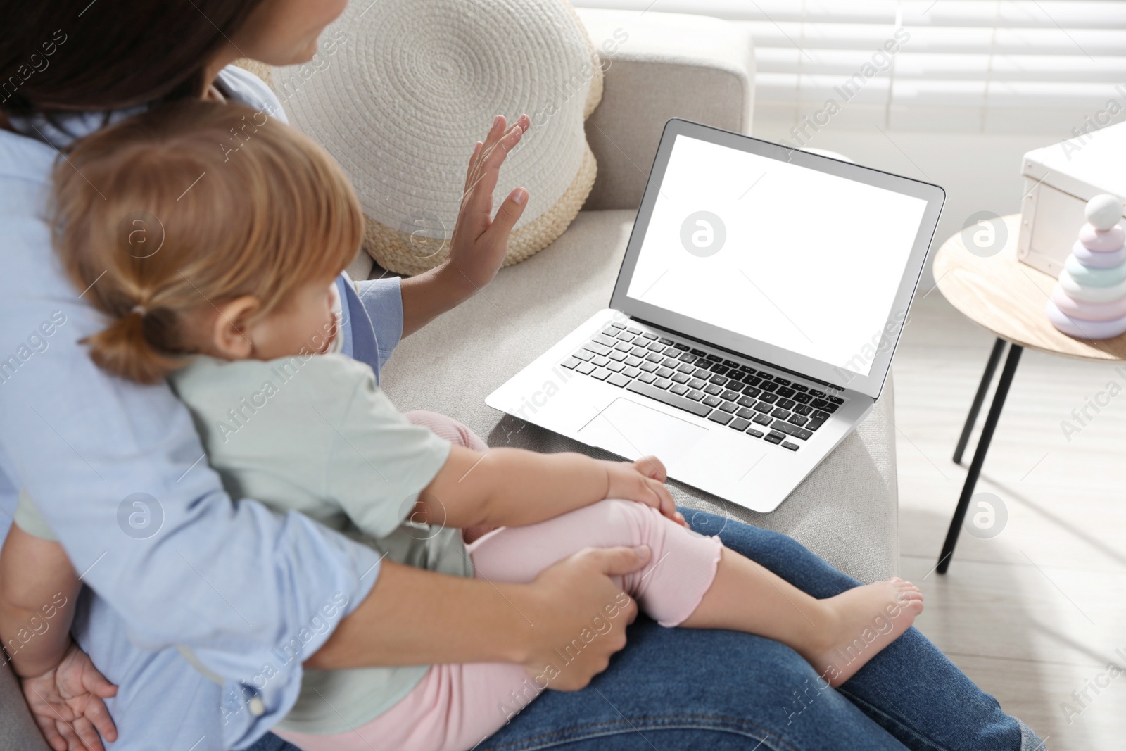 Photo of Mother and daughter with laptop on sofa at home. Pediatrician online consultation