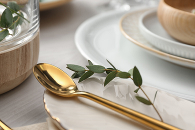 Photo of Elegant spoon with green leaves on table, closeup. Festive setting