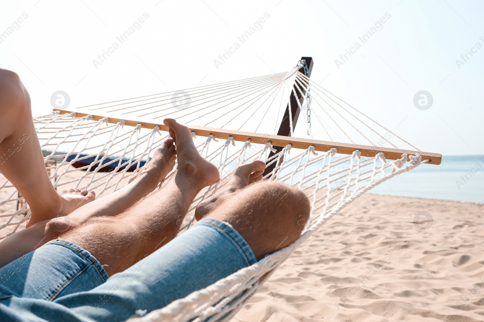 Photo of Young couple relaxing in hammock on beach, closeup