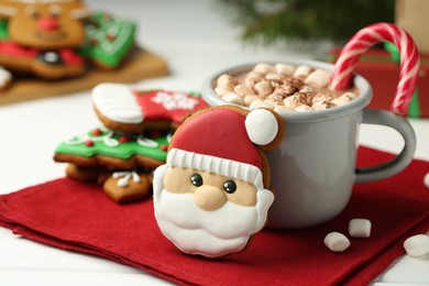 Photo of Tasty homemade Christmas cookie and hot chocolate with marshmallows on white wooden table, closeup