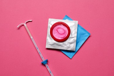 Photo of Contraception choice. Condoms and intrauterine device on magenta background, flat lay