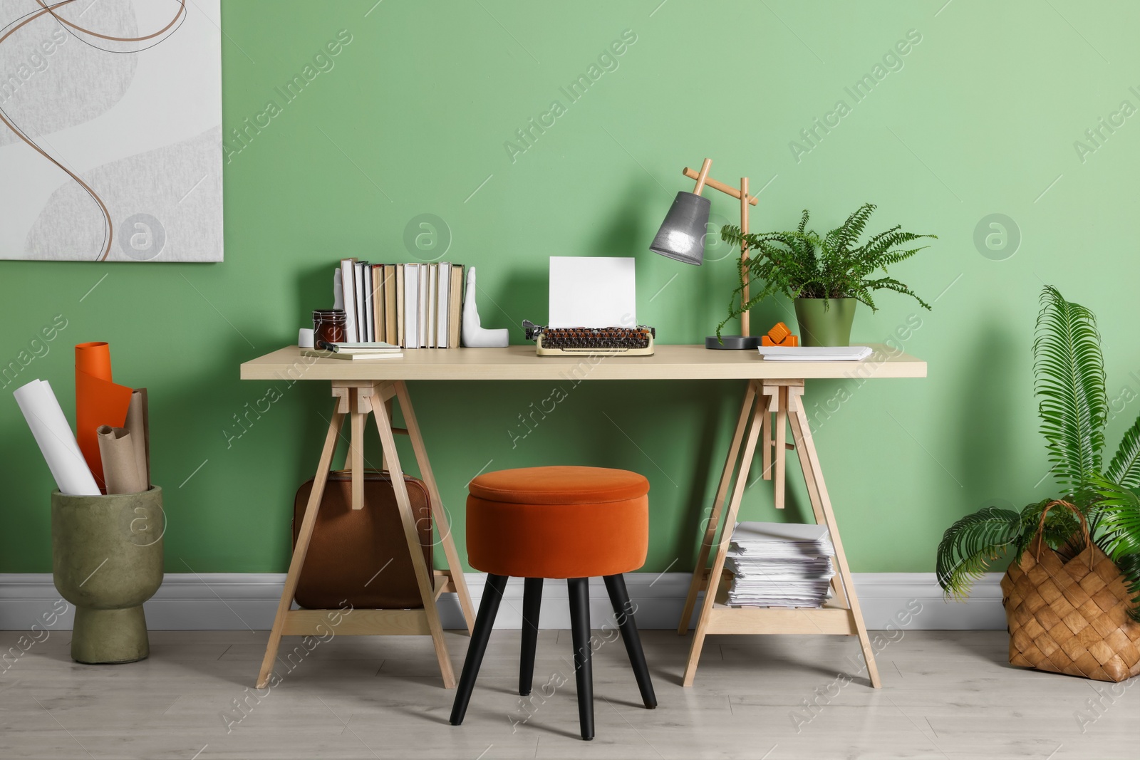 Photo of Writer's workplace with typewriter on wooden desk near pale green wall in room