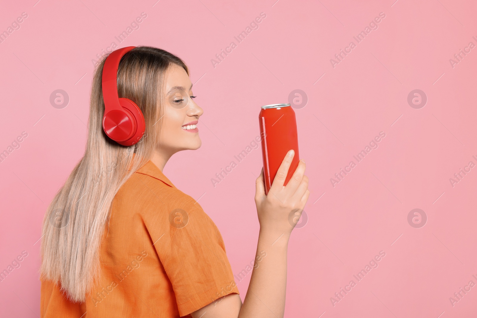 Photo of Beautiful happy woman holding red beverage can on pink background. Space for text