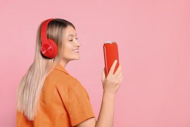 Photo of Beautiful happy woman holding red beverage can on pink background. Space for text