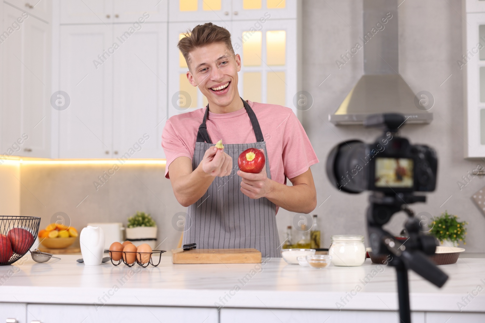 Photo of Smiling food blogger explaining something while recording video in kitchen