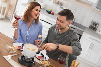 Happy couple enjoying fondue dinner at home