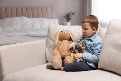 Photo of Cute little boy playing with stethoscope and toy bunny at home. Future pediatrician