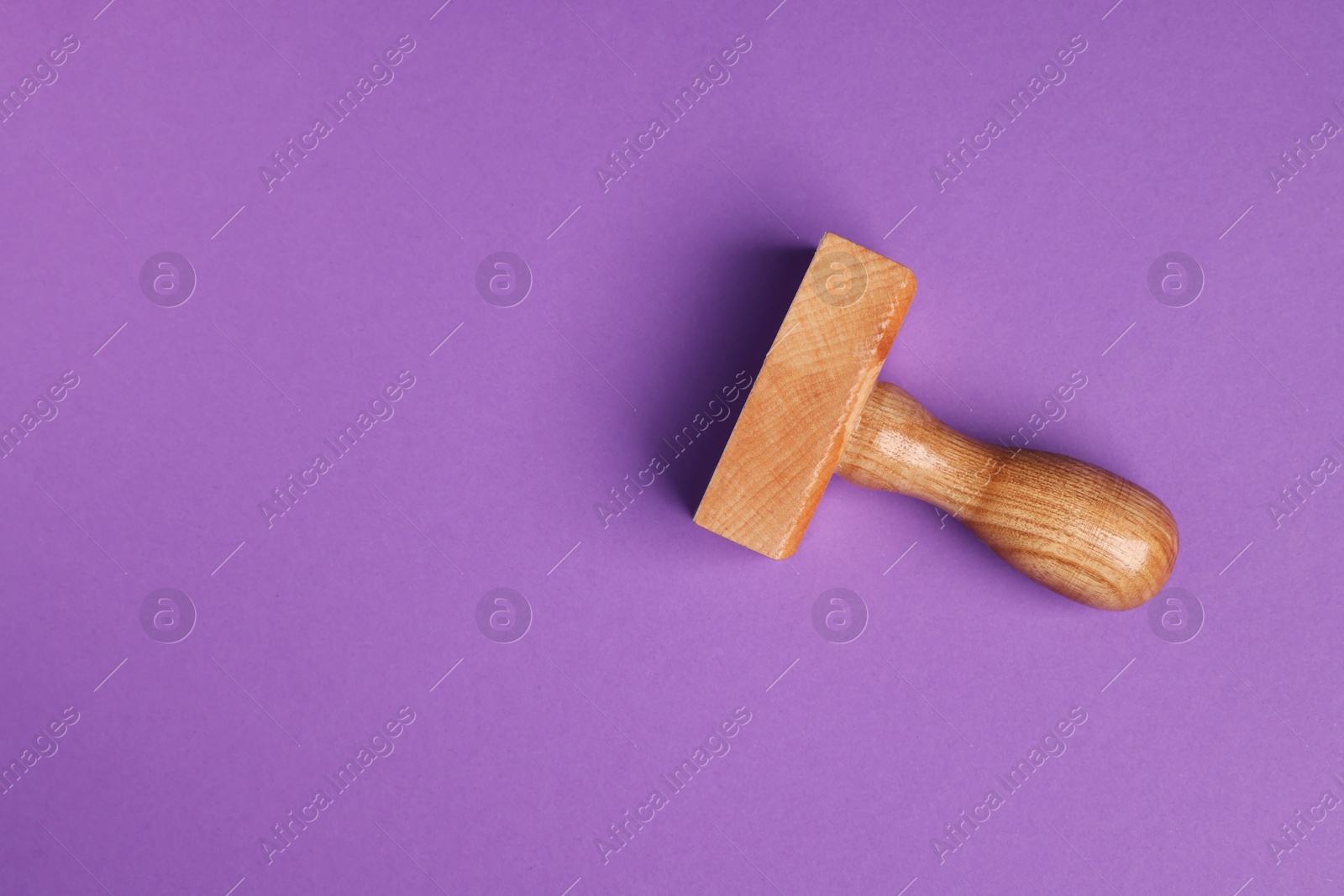 Photo of One wooden stamp tool on purple background, top view. Space for text