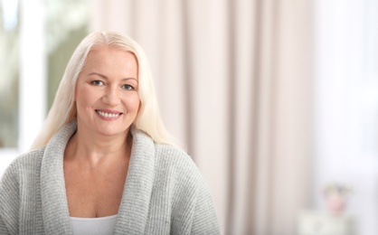 Portrait of beautiful older woman against blurred background with space for text