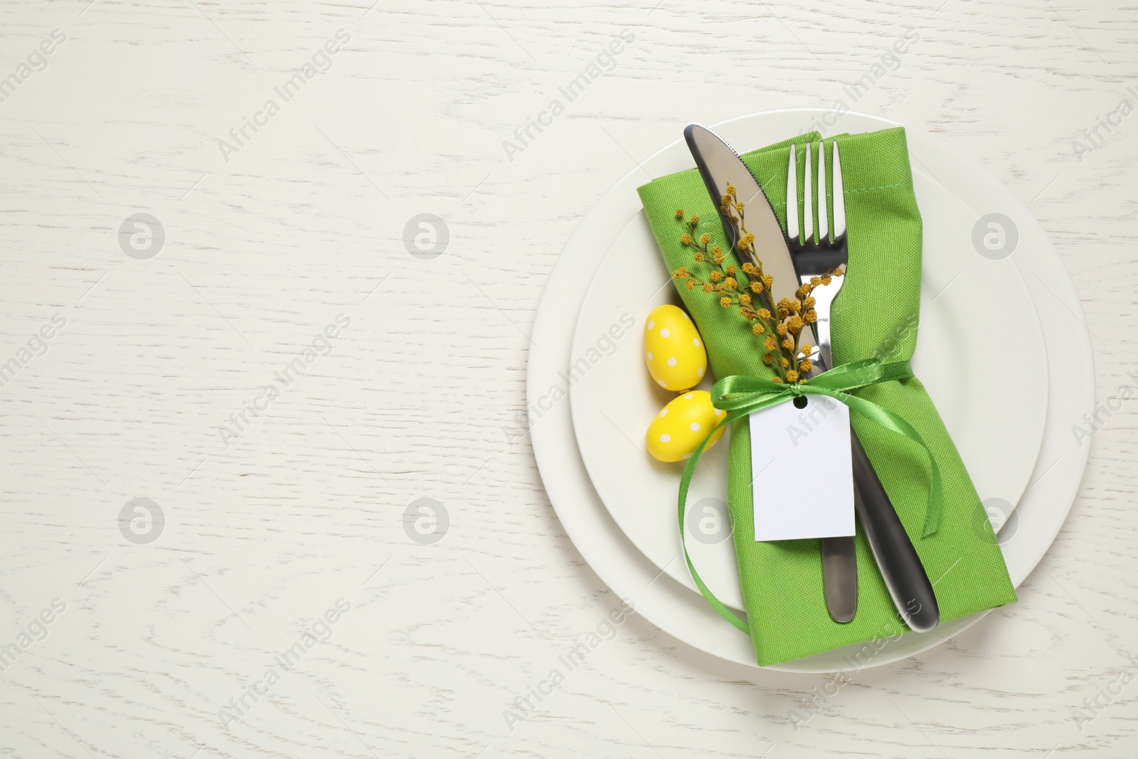 Photo of Festive Easter table setting with beautiful mimosa flowers and painted eggs, top view. Space for text