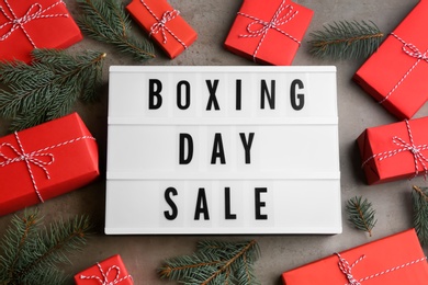Photo of Lightbox with phrase BOXING DAY SALE and Christmas decorations on grey background, flat lay