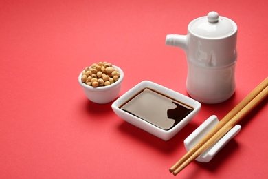 Photo of Tableware with soy sauce and beans on color background. Space for text