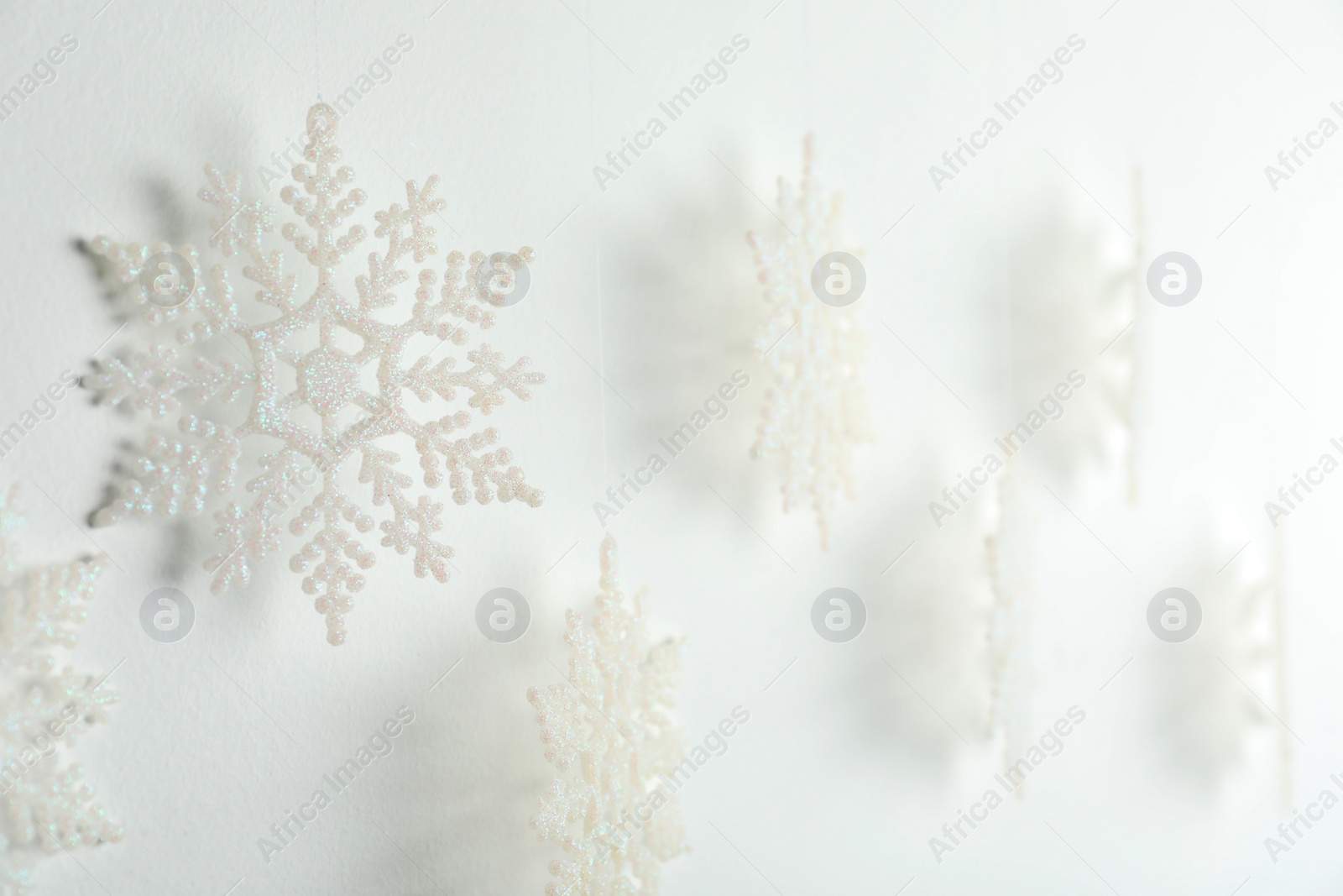 Photo of Beautiful decorative snowflakes hanging on white background, closeup