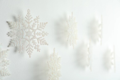 Photo of Beautiful decorative snowflakes hanging on white background, closeup