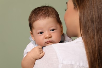 Photo of Mother holding her cute newborn baby on olive background