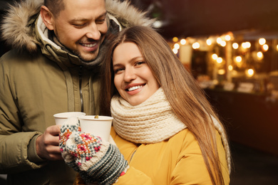 Photo of Happy couple with mulled wine at winter fair