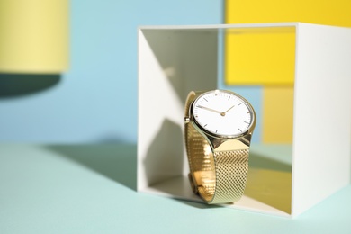 Photo of Stylish golden wristwatch on color background. Space for text