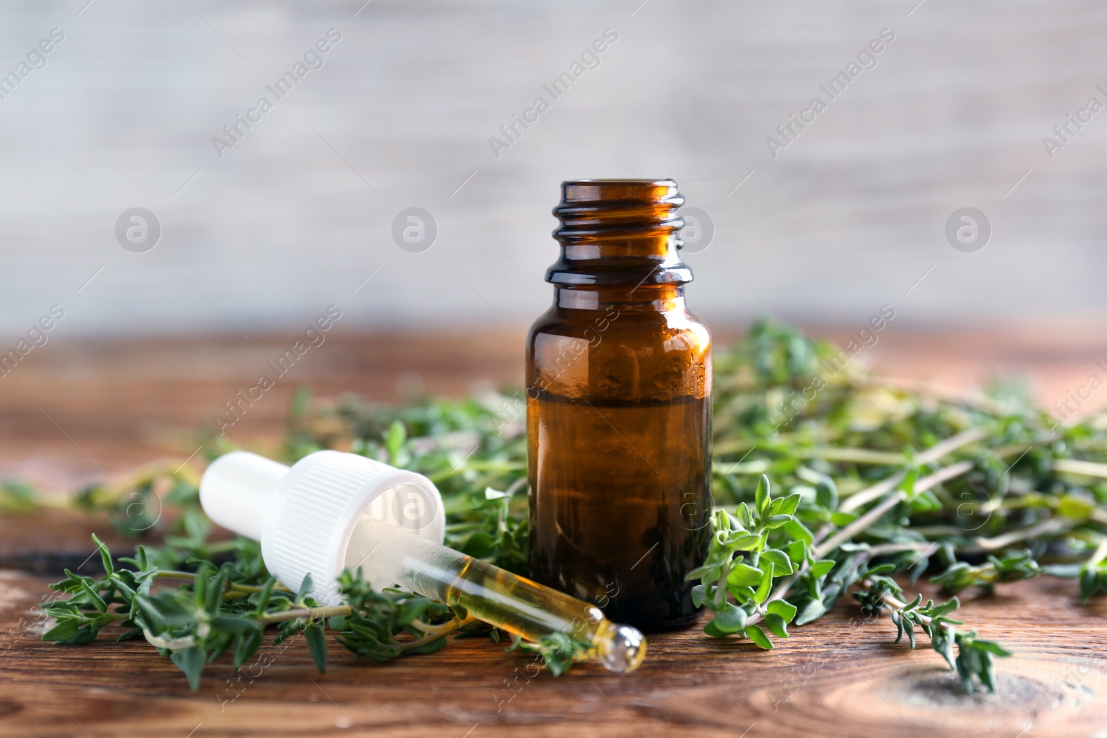 Photo of Bottle of essential oil with thyme on wooden table