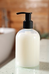 Photo of Dispenser of liquid soap on white table in bathroom