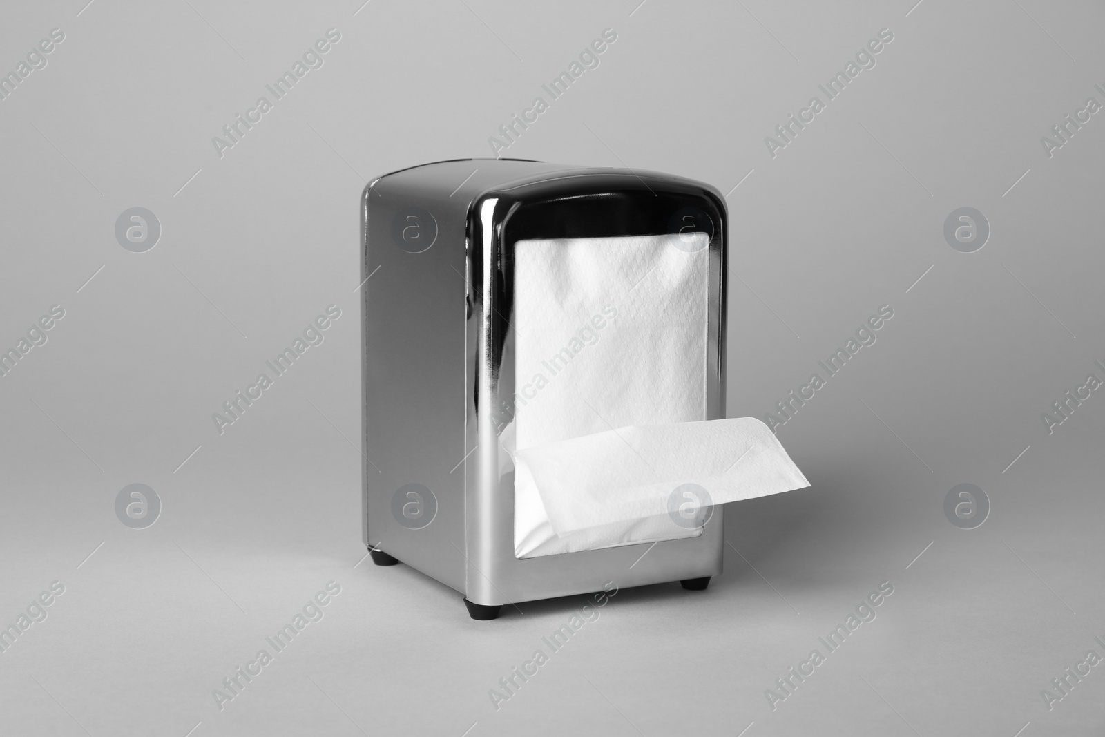 Photo of Napkin holder with paper serviettes on gray background