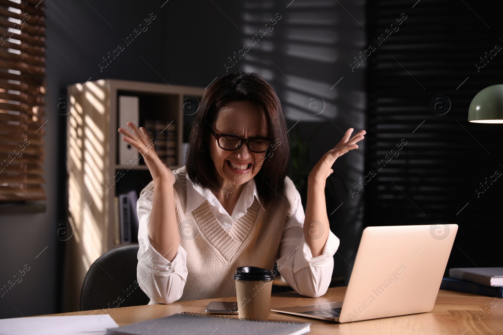 Photo of Emotional businesswoman working on laptop in office. Online hate concept