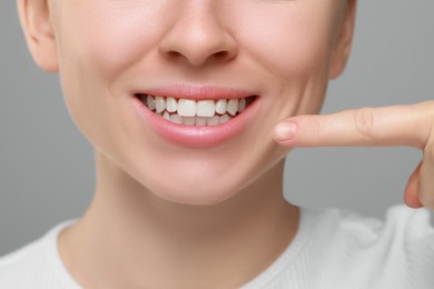 Woman showing healthy gums on grey background, closeup