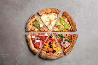 Photo of Slices of different delicious pizzas on grey table, flat lay