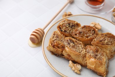 Eastern sweets. Pieces of tasty baklava on white tiled table, closeup. Space for text