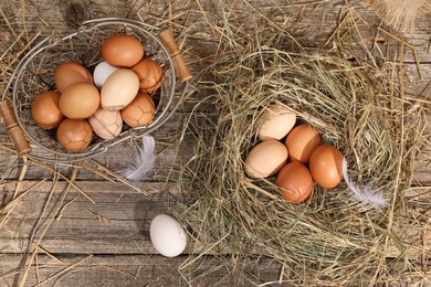 Photo of Fresh chicken eggs and dried hay on wooden table, flat lay