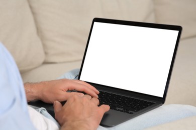 Photo of Man using laptop on sofa, closeup view