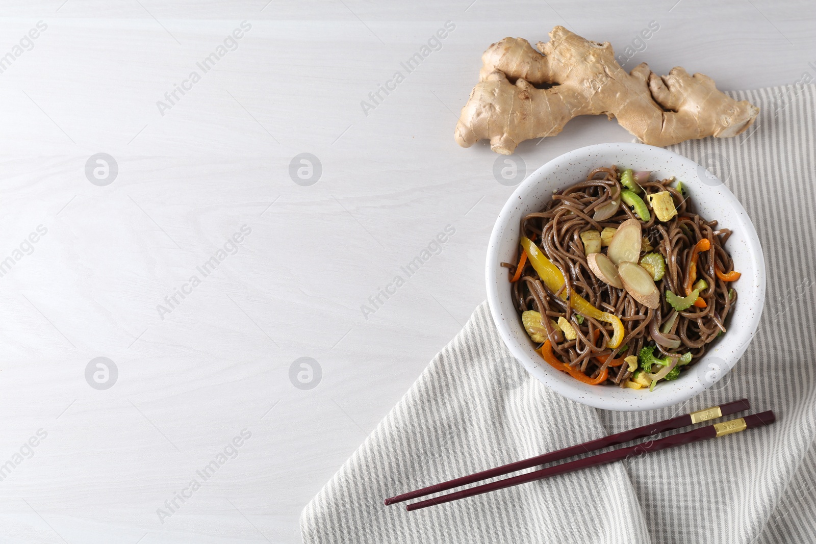 Photo of Stir-fry. Delicious cooked noodles with chicken and vegetables in bowl served on light wooden table, flat lay. Space for text