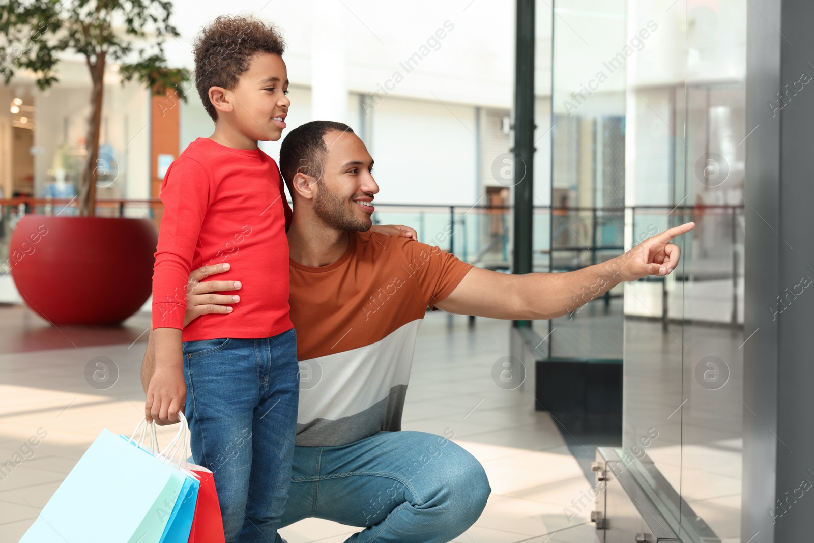 Photo of Family shopping. Happy father and son with colorful bags in mall