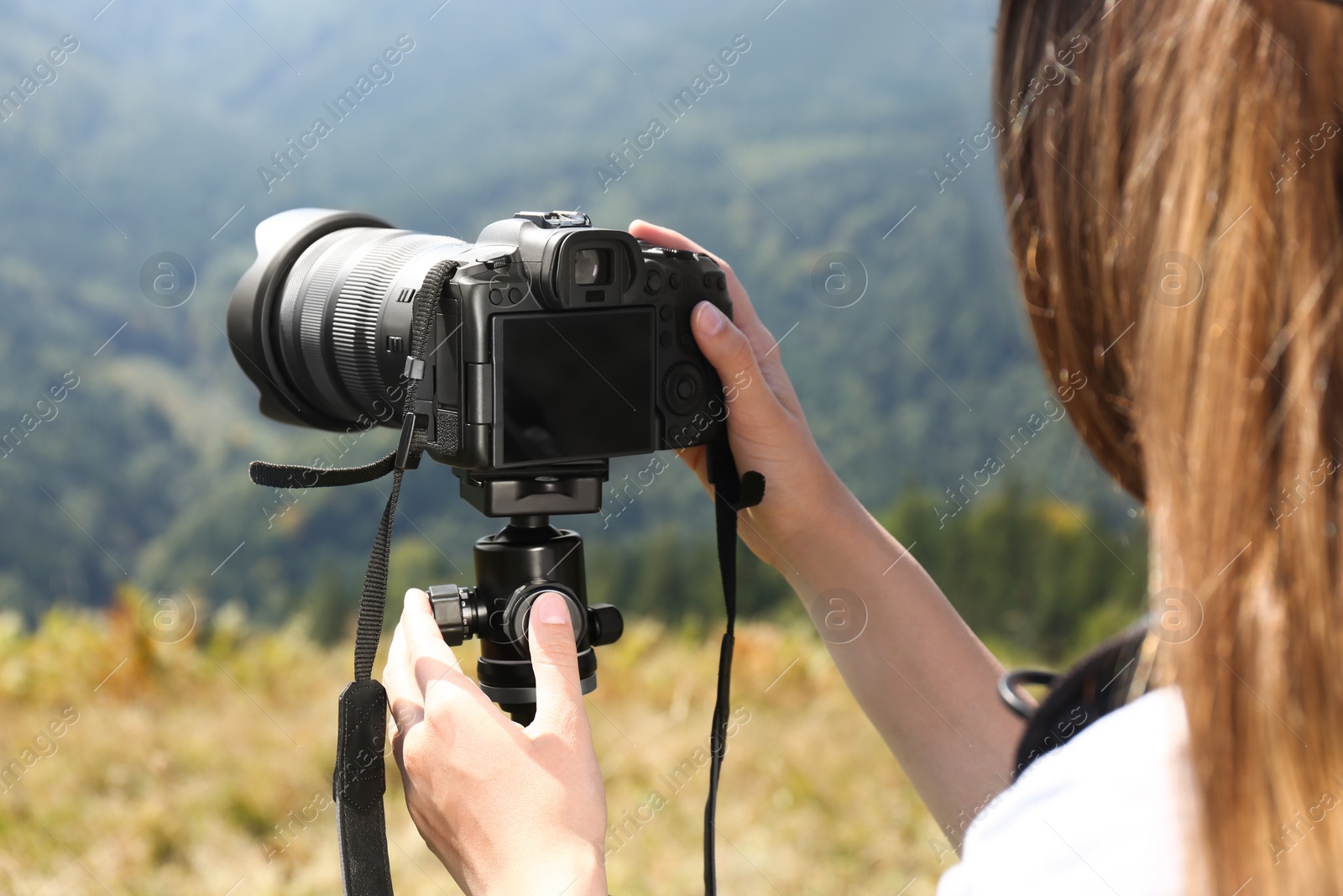 Photo of Woman taking photo of nature with modern camera on stand outdoors