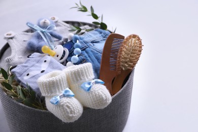 Box with baby clothes, booties and accessories on grey background