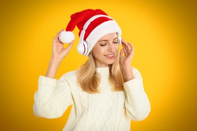 Photo of Happy woman with headphones on yellow background. Christmas music