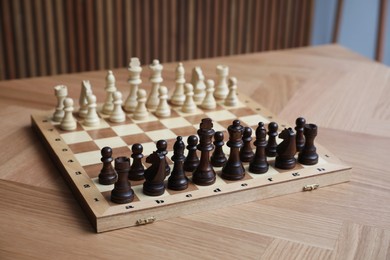 Chess board with pieces on wooden table