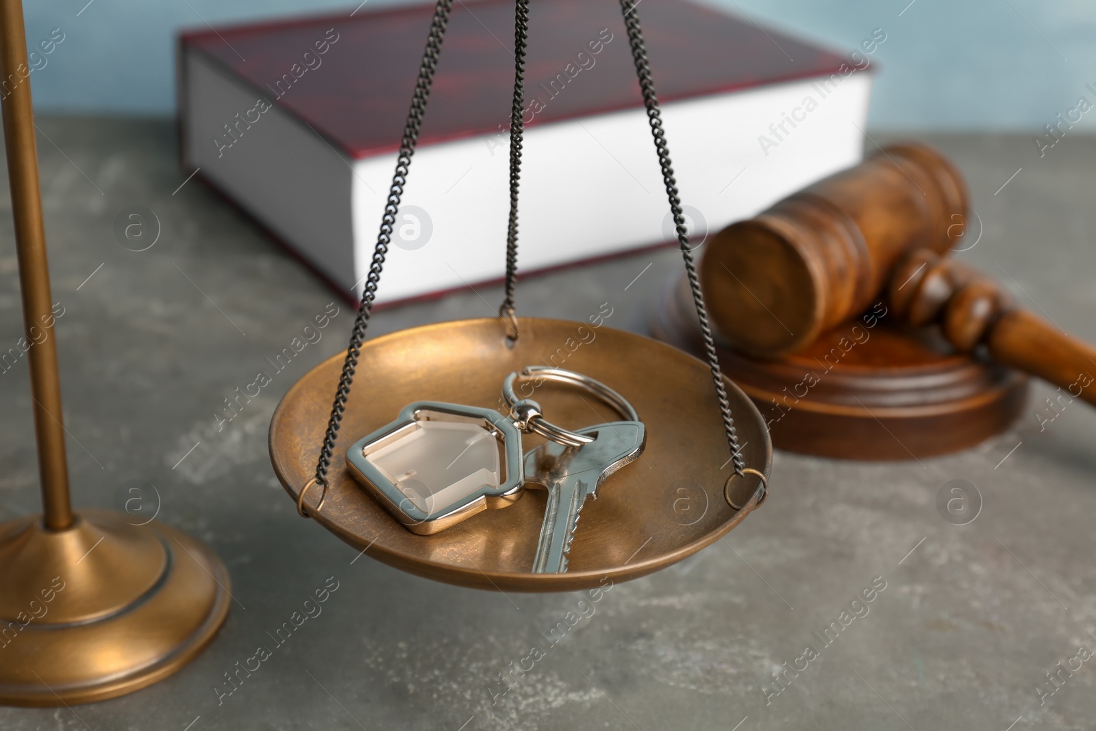 Photo of Scales of justice with house key on table, closeup. Estate law concept